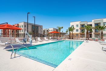 A large swimming pool surrounded by lounge chairs and umbrellas.
